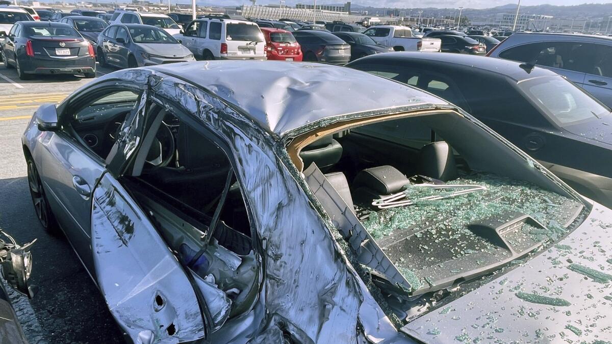 A damaged car is seen in a airport parking lot after debris from a tyre which fell from a Boeing 777 landed on it at San Francisco International Airport last month. — AP
