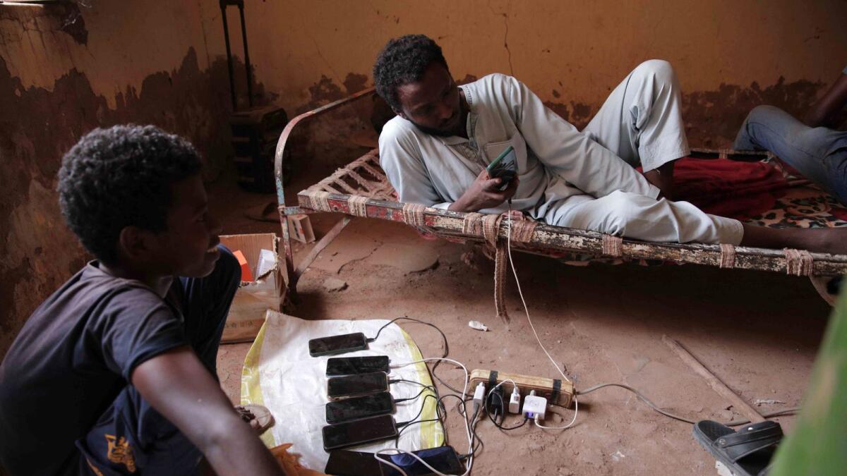 People charge their mobile phones at a house in Khartoum. — AP file
