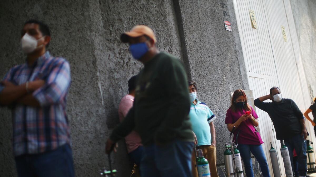People queue to fill oxygen tanks for relatives due to an increase in coronavirus disease (COVID-19) infection rates in Mexico, outside a medical supply store in Mexico City, December 21, 2020.