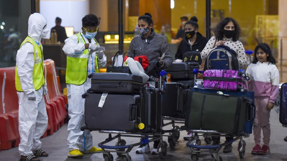 Health workers keep vigil as passengers exit the Chhatrapati Shivaji International Airport upon their arrival from London in Mumbai on December 22, 2020. (Photo by Punit PARANJPE / AFP)
