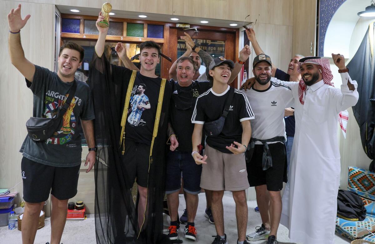 An Argentian fan raises a mock world cup trophy as he wears a a traditional black and gold Arab cloak (bisht). Photo: AFP