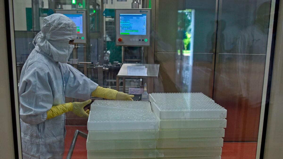 An employee in protective gear works on an assembly line for manufacturing vials of Covishield, AstraZeneca-Oxford's Covid-19 coronavirus vaccine at India's Serum Institute. Photo: AFP