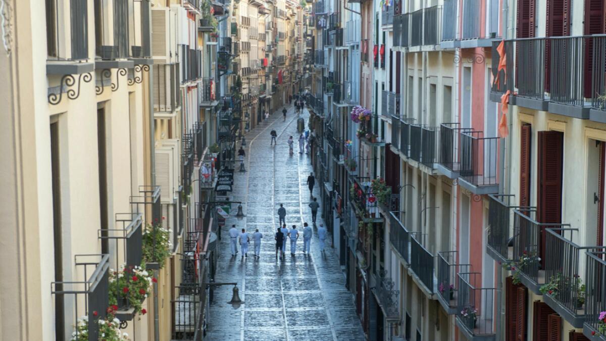 Participants walk along Estafeta street during the symbolic celebration of the first bullrun of the San Fermin festival in Pamplona, northern Spain.  The 2020 edition of the San Fermin Festival has been cancelled as part of preventive measures to fight the spread of the novel coronavirus. Photo: AFP
