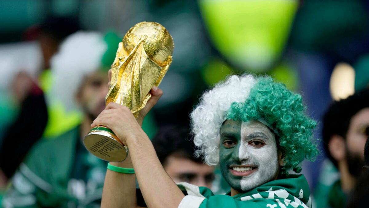 A Saudi Arabia fan holds up a copy of the World Cup trophy prior of the World Cup group C soccer match between Poland and Saudi Arabia. — AP
