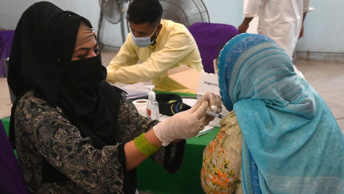 A health worker inoculates a woman with a dose of the Covishield AstraZeneca vaccine  in Lahore. Photo: AFP