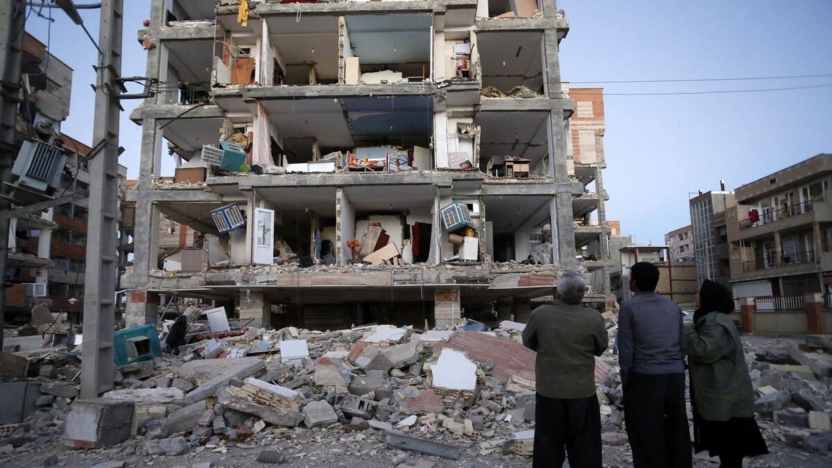 People look at destroyed buildings after an earthquake at the city of Sarpol-e-Zahab in western Iran.- AP
