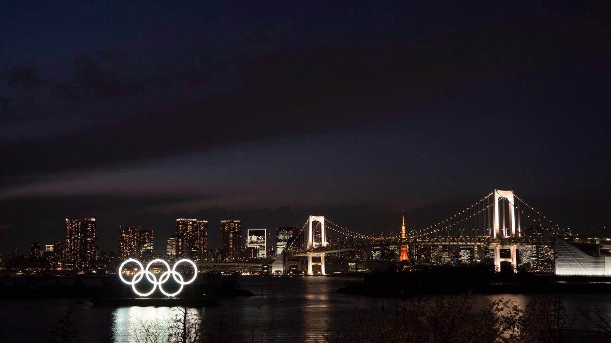 The Olympic rings float in the water near the Rainbow Bridge in the Odaiba section of Tokyo. — AP