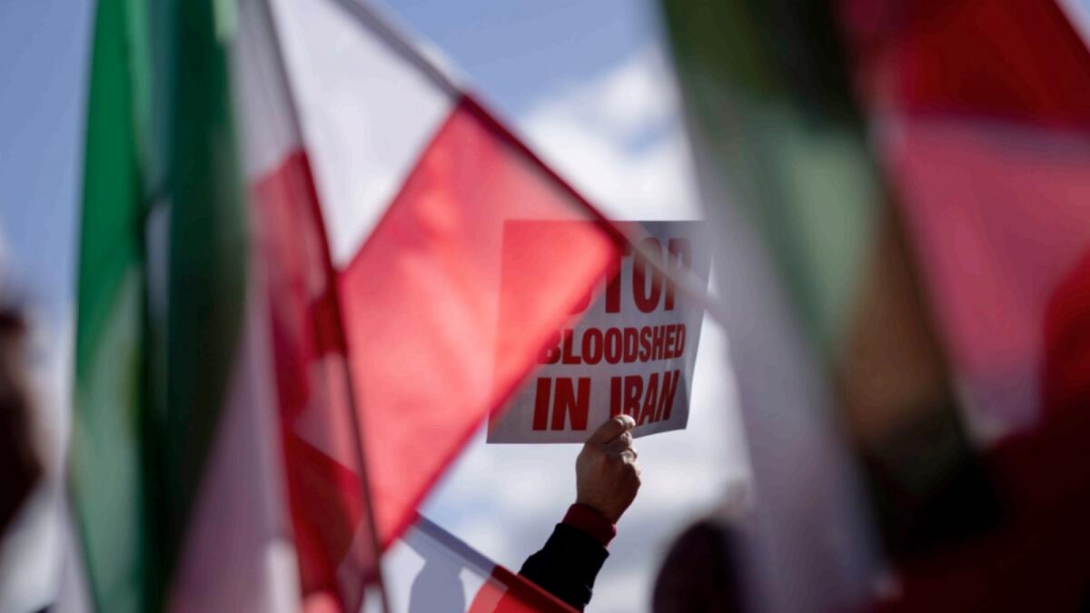 A protestor holds a placard reading 'Stop Bloodshed in Iran' during a demonstration in The Hague, Netherlands. — AP