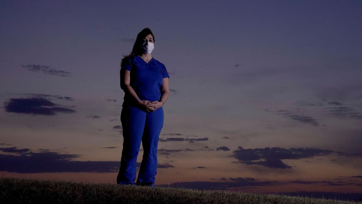 Emergency room nurse L'Erin Ogle stands at dawn before starting her 12-hour shift at a nearby hospital on March 9, 2021, in Overland Park, Kan.