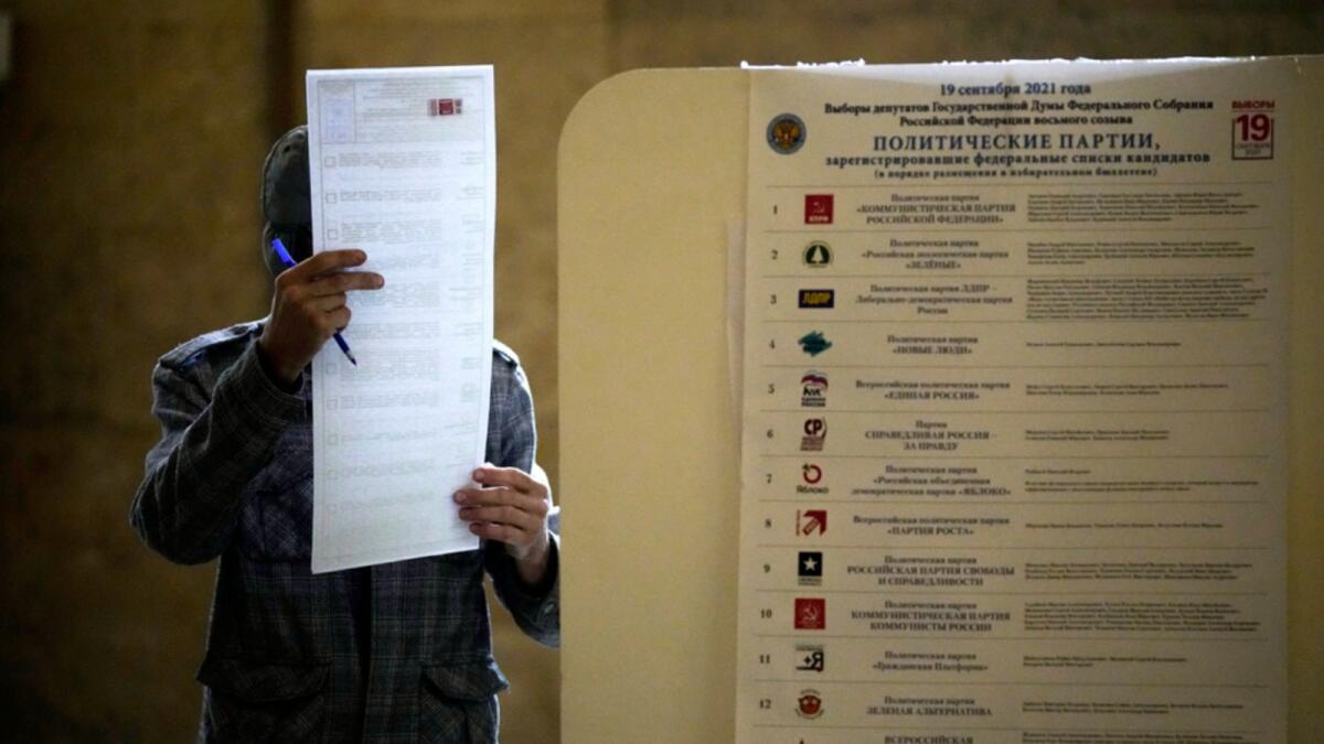 A man reads his ballot at a polling station during the Parliamentary elections in Moscow. — AP