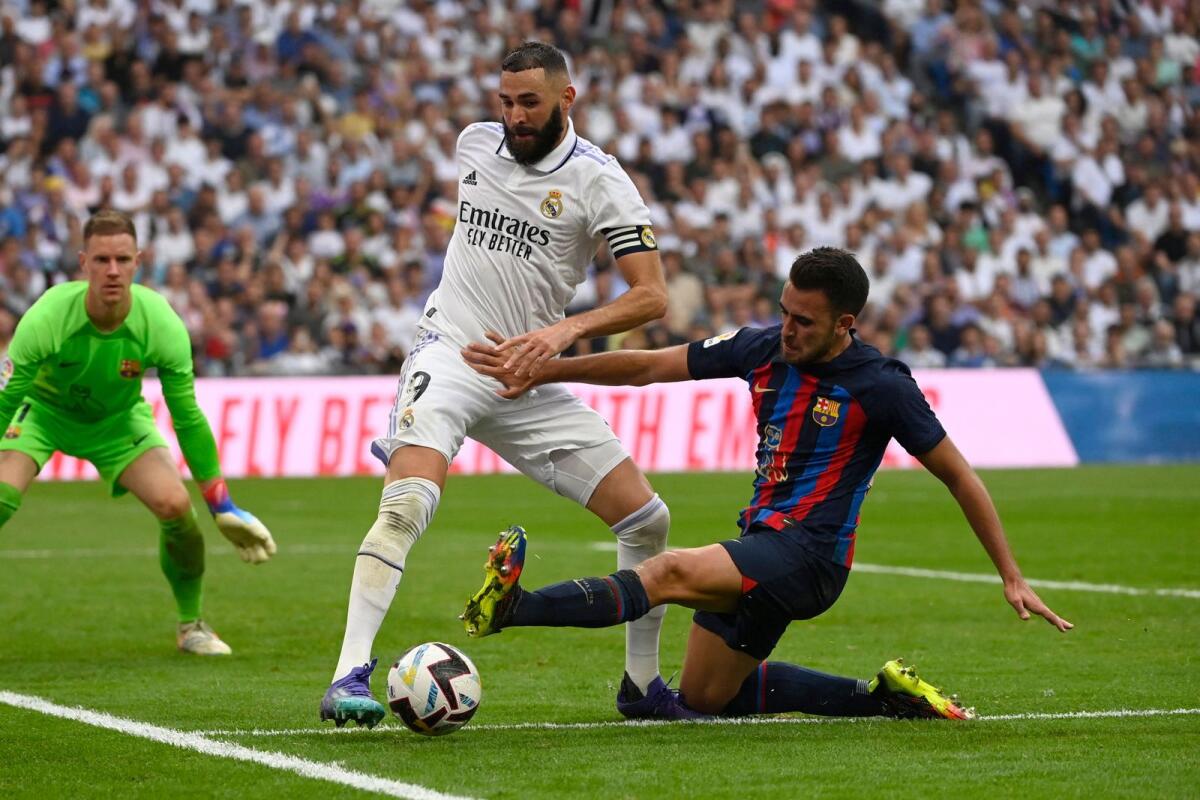 Real Madrid's Karim Benzema (centre) vies for the ball with Barcelona's Eric Garcia. (AFP)