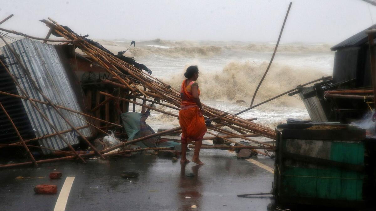 A woman stands next to her stall damaged by heavy winds, in Balasore district in Odisha.