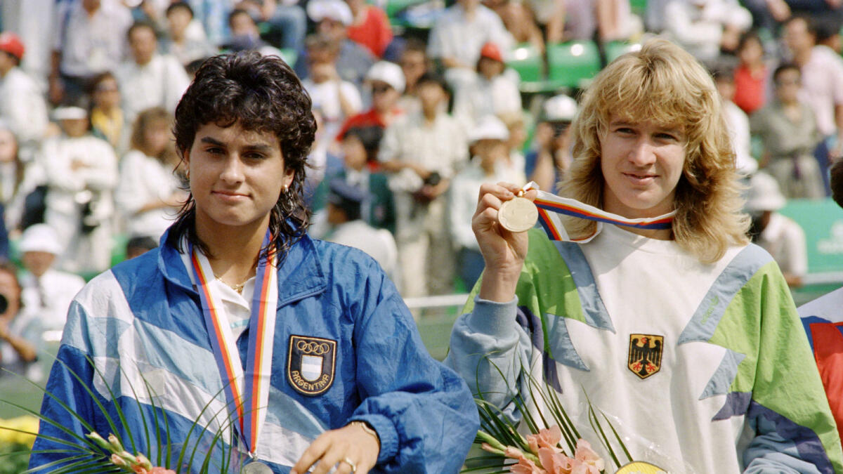 German tennis woman champion Stefi Graff (R) shows off the gold medal during the awarding ceremonies for the women' s singles on October 01, 1988 at the Seoul Olympic Tennis court. Argentina' s Gabriela Sabatini (L) won Silver. / AFP PHOTO / Chris Wilkins