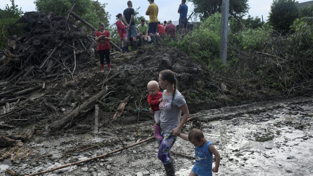 A woman and children walk along a street in the settlement of Lanchyn affected by heavy rainfall and flooding in Ivano-Frankivsk Region, Ukraine. Photo: Reuters