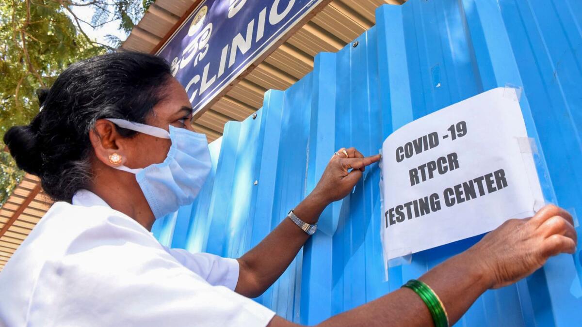 A medic puts up a notice at a Covid-19 testing centre of the district hospital in Chikkamagaluru on Saturday. Photo: PTI