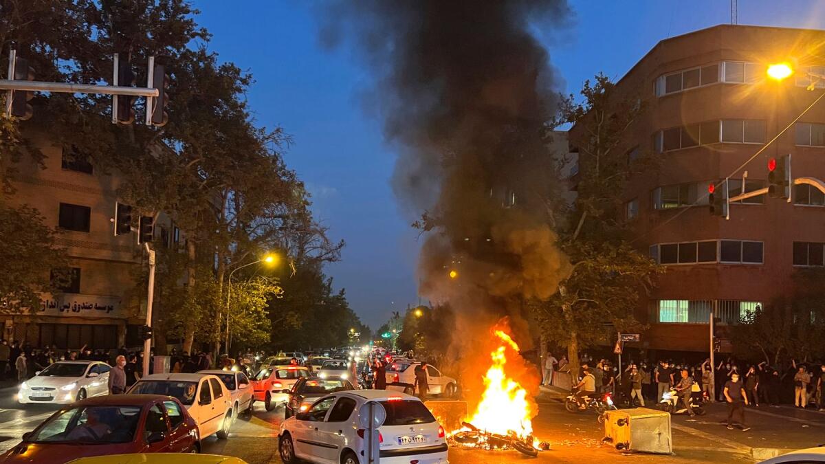 A police motorcycle is burning during a protest in downtown Tehran, Iran. – AP