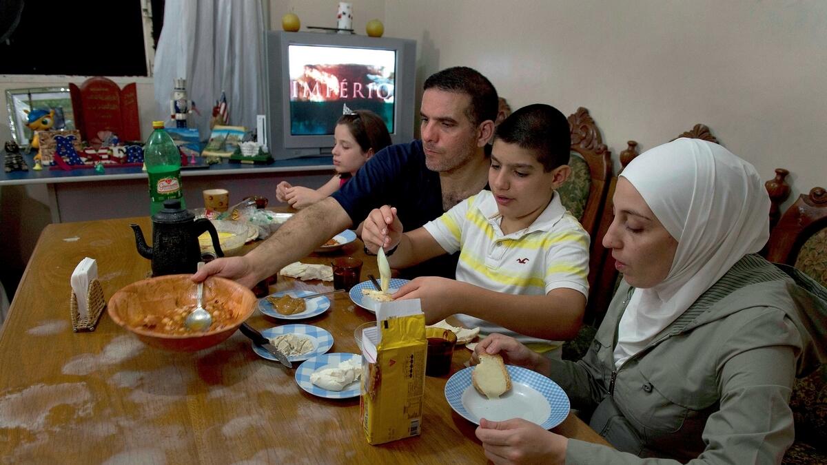 FEELS LIKE HOME: Syrian refugee Talal Al Tinawi has dinner with his wife Ghazal and their children Yara and Riad at home in Sao Paulo, Brazil. Brazil host over 1,700 Syrian refugees. — AFP 