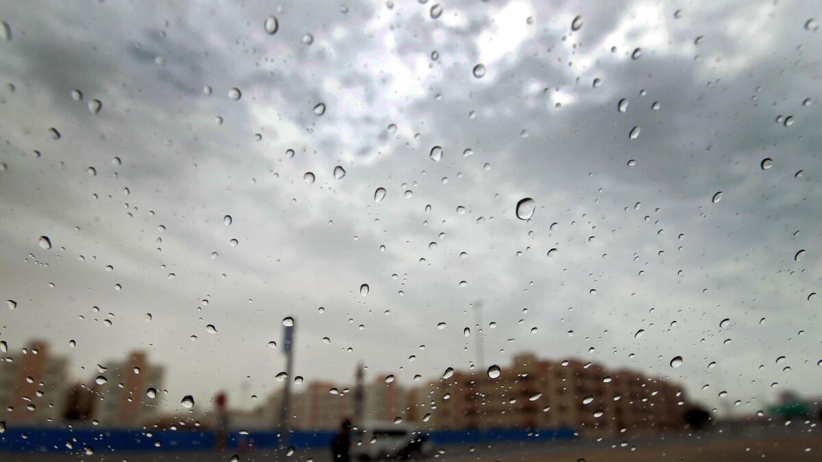 COOLING EFFECT ... Rain drops on a car windshield with the cloudy sky in the background in Al Quoz area. Temperature across the country will further drop by 3 degree Celsius today.  — Photo by Rahul Gajjar