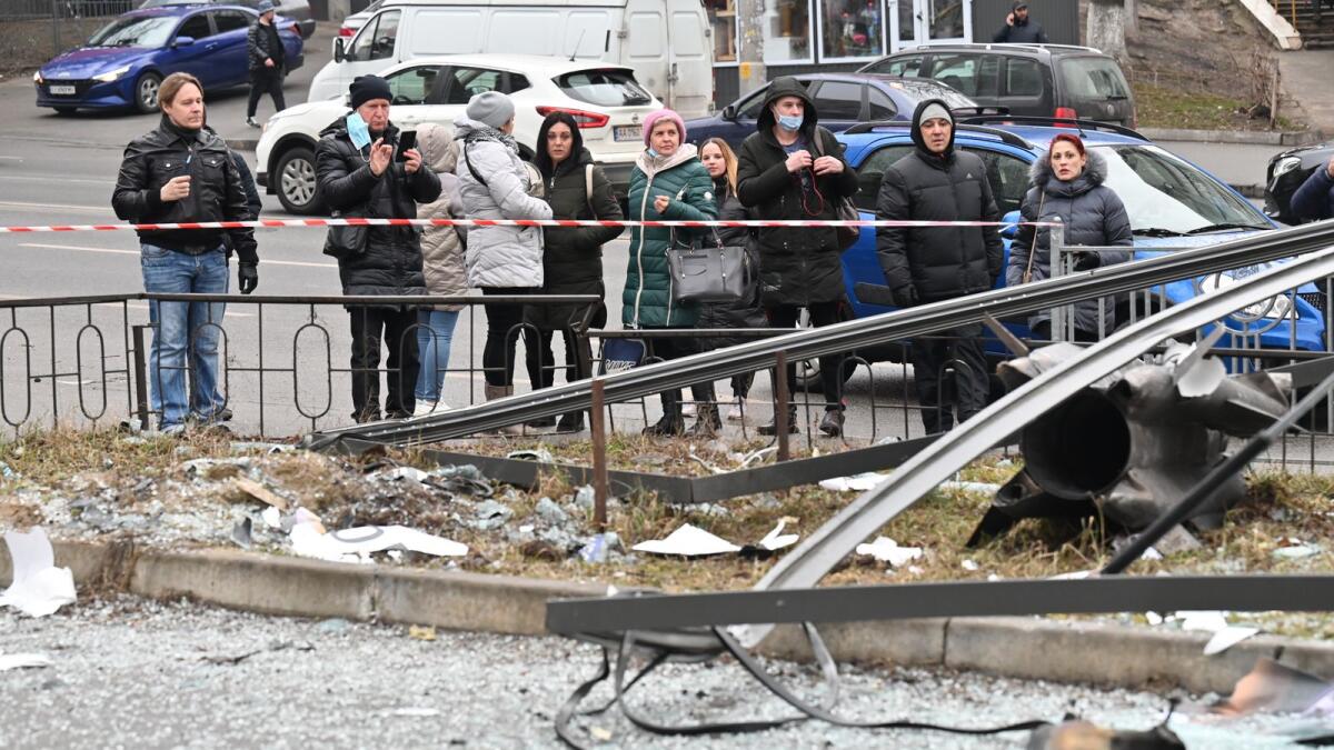 People react standing behind the cordoned off area around the remains of a shell in Kyiv on February 24, 2022Photo: AFP