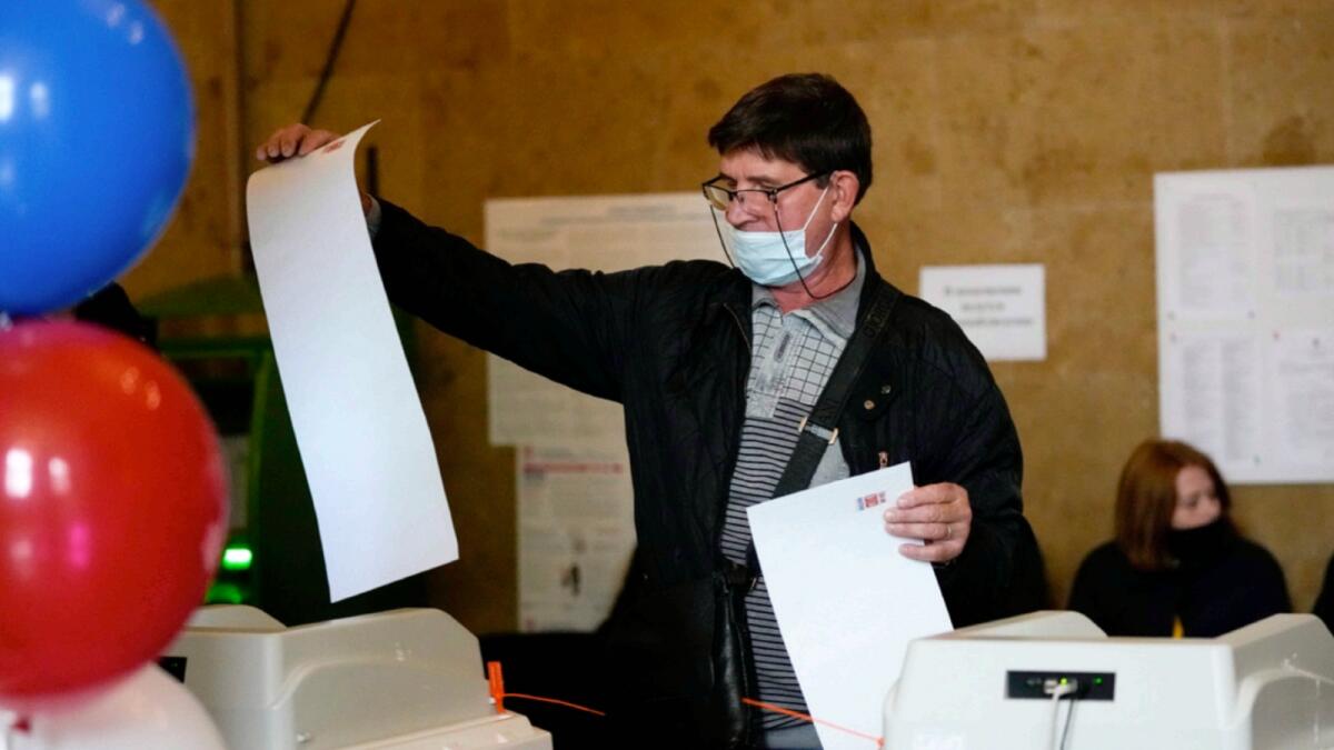 A man casts his ballots at a polling station during the Parliamentary elections in Moscow. — AP