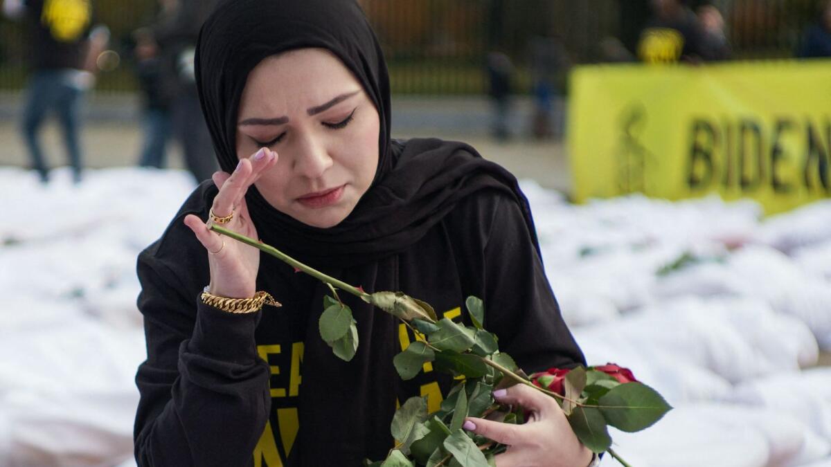 An activist wipes her eye while placing flowers on white-shrouded body bags representing victims in the Israel-Hamas conflict, in front of the White House in Washington, DC. — AFP