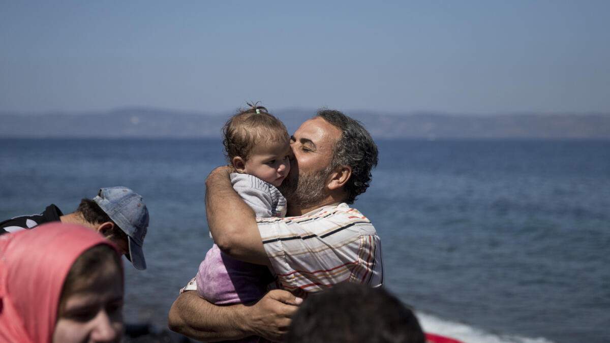 A Syrian man kisses his daughter after they arrived aboard a dinghy from Turkey, to the island of Lesbos, Greece, on Saturday, Sept. 19, 2015. AP photo