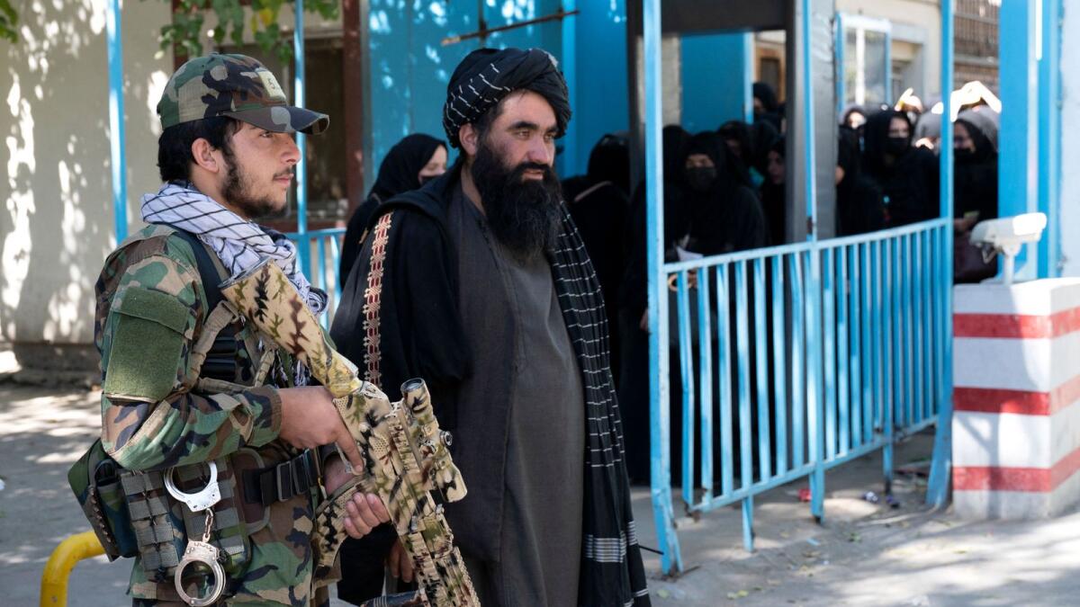 Taliban fighters stand guard as female students arrive for entrance exams at Kabul University in Kabul in October. — AFP file