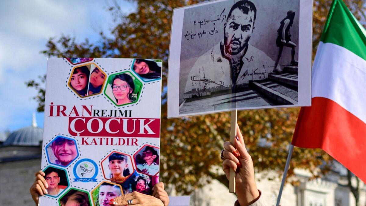 People hold placards bearing portraits of Iranian rapper Toomaj Salehi (R), who is arrested in Iran, and portraits of children (L), who were killed during the protests in Iran, during a rally in support of Iranian women in Istanbul, on November 26, 2022. AFP