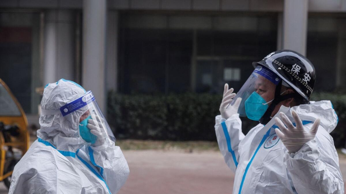 Pandemic prevention workers in protective suits get ready to enter an apartment building that went into lockdown as outbreaks continue in Beijing. — Reuters