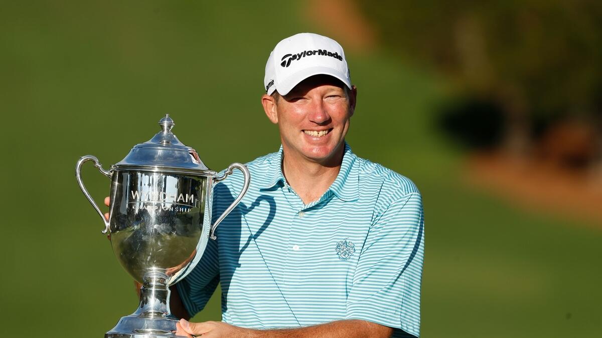 Jim Herman of the United States celebrates with the trophy on the 18th green after winning during the final round of the Wyndham Championship