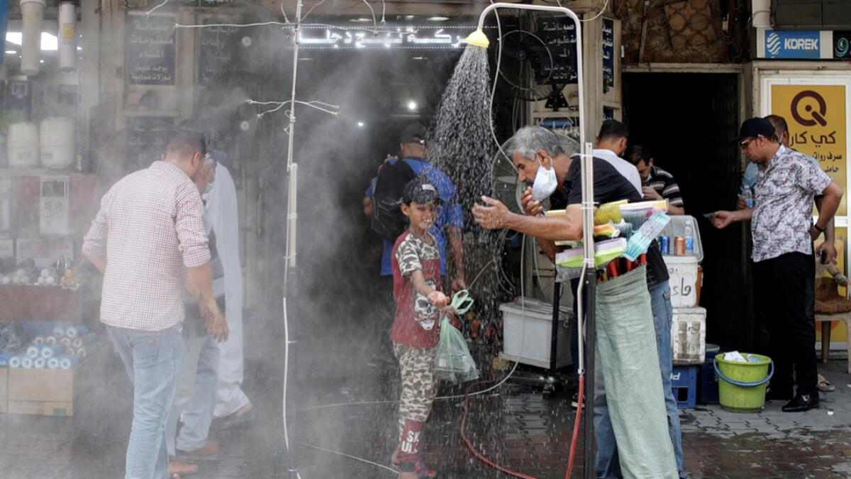 People cool off under an outdoor shower as the temperature soars in Baghdad, Iraq. Photo: Reuters
