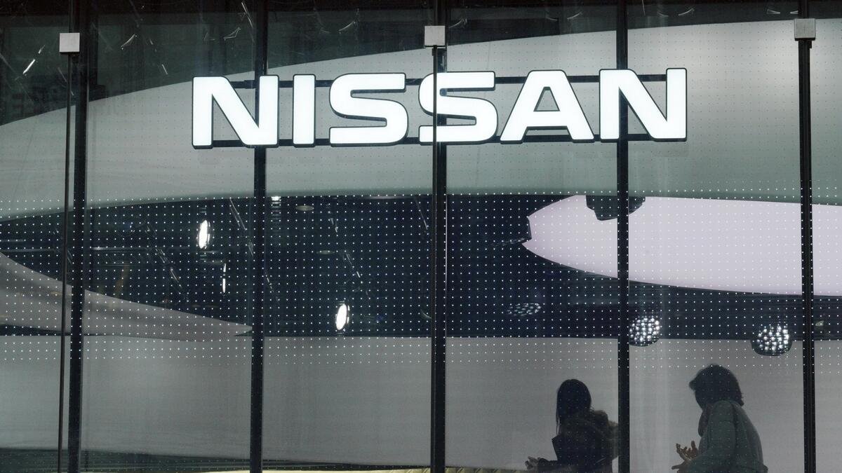Visitors walk near the logo of Nissan at a Nissan showroom in Tokyo.-AP 