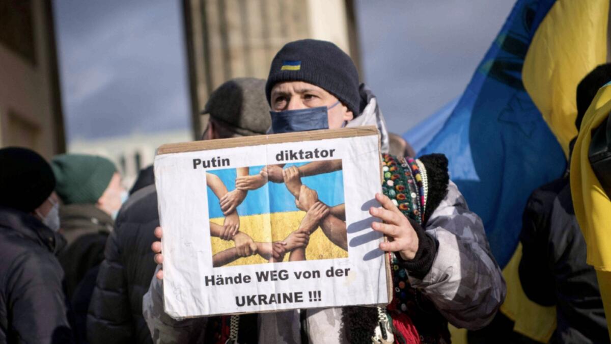 A protester holds a poster reading 'Putin dictator - Hands off Ukraine'! during a demonstration for peace in Ukraine in front of the Brandenburger Gate in Berlin. — AFP