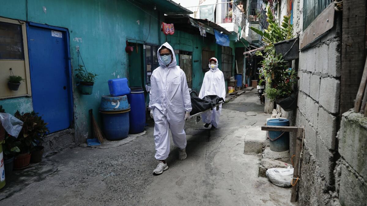 Funeral home workers in protective suits carry a body during the start of a lockdown due to a rise in Covid cases in the city of Navotas, Manila, Philippines. Photo: AP