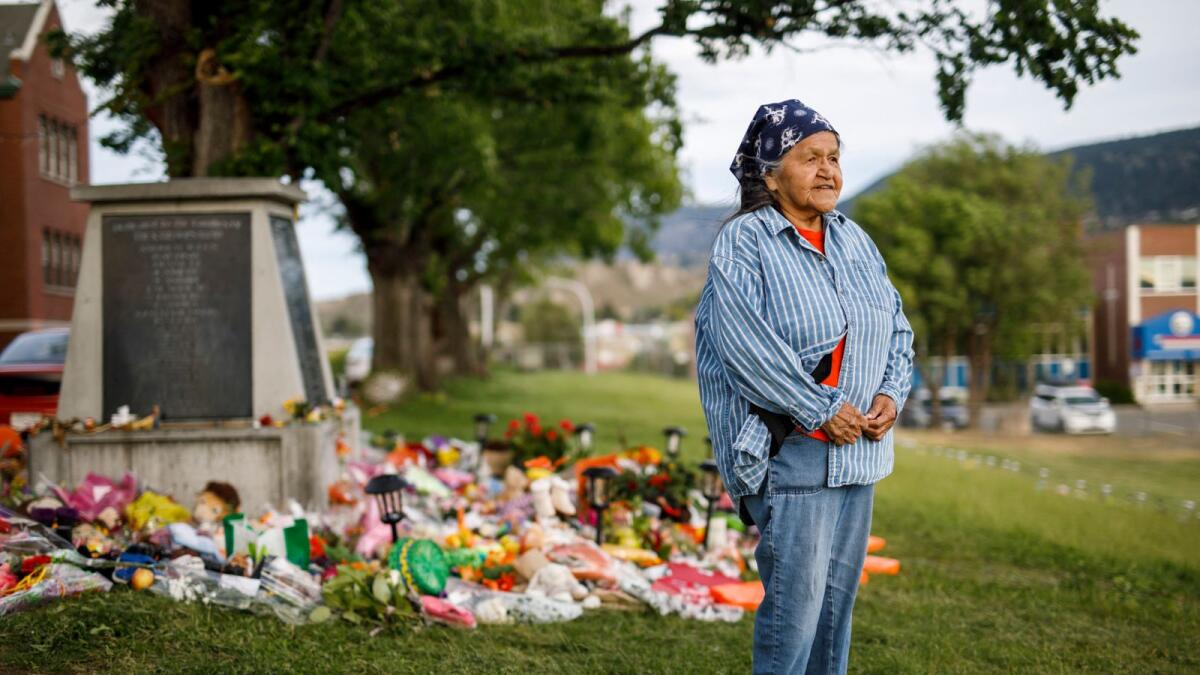 Kamloops Indian Residential School survivor Evelyn Camille stands next to a makeshift memorial at the school to honour children whose remains have been discovered near the facility. Photo: AFP