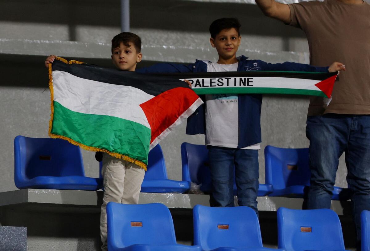 Young Palestine fans display a scarf and a flag at the stadium in Sharjah. — Reuters