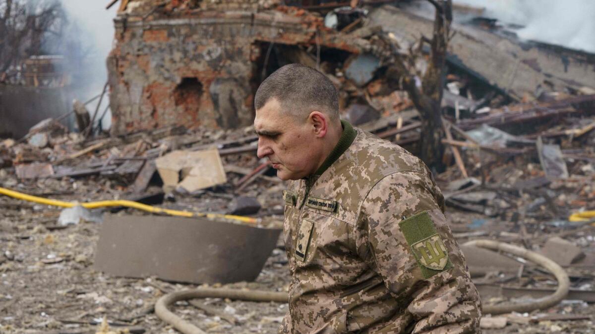 Ukraine army public affairs officer Valentin Yermolenko walks in front of a destroyed shoe factory following an airstrike in Dnipro on March 11, 2022. Civilian targets came under Russian shelling in the central Ukrainian city of Dnipro on March 11, killing one, emergency services said, in what appeared to be the first direct attack on the city. (Photo by emre caylak / AFP)
