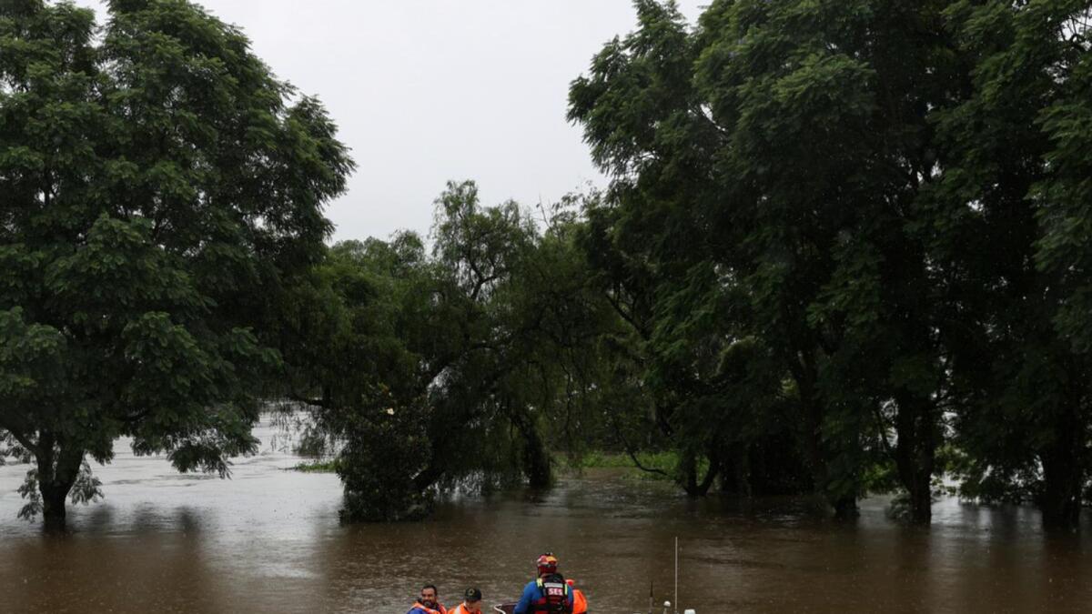 Emergency Service personnel transport a doctor by boat in the suburb of Windsor, so he can attend to patients unreachable by car. Photo: Reuters