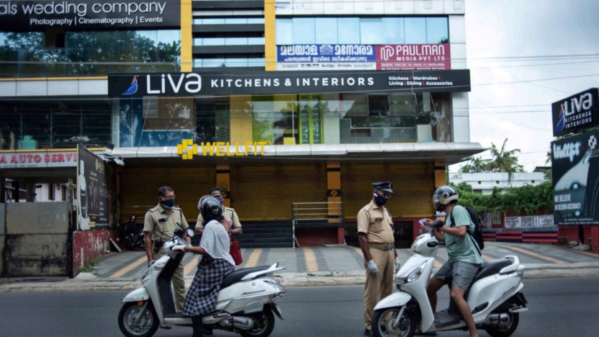 Policemen check the credentials of commuters during a lockdown imposed to curb the spread of coronavirus in Kochi. — PTI