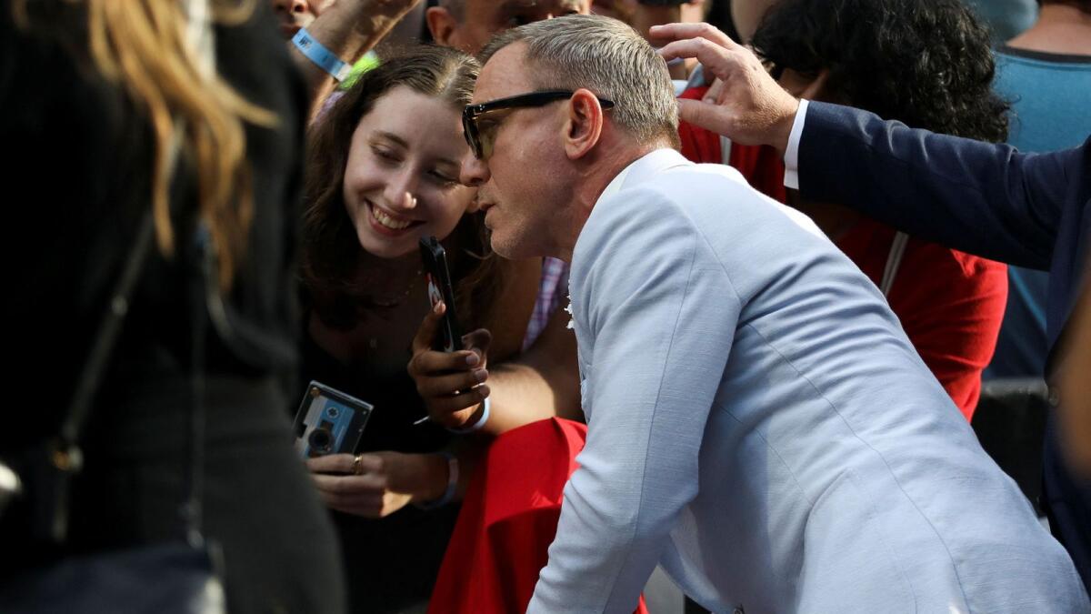 Daniel Craig poses for a picture with a fan as he attends the world premiere of Glass Onion: A Knives Out Mystery