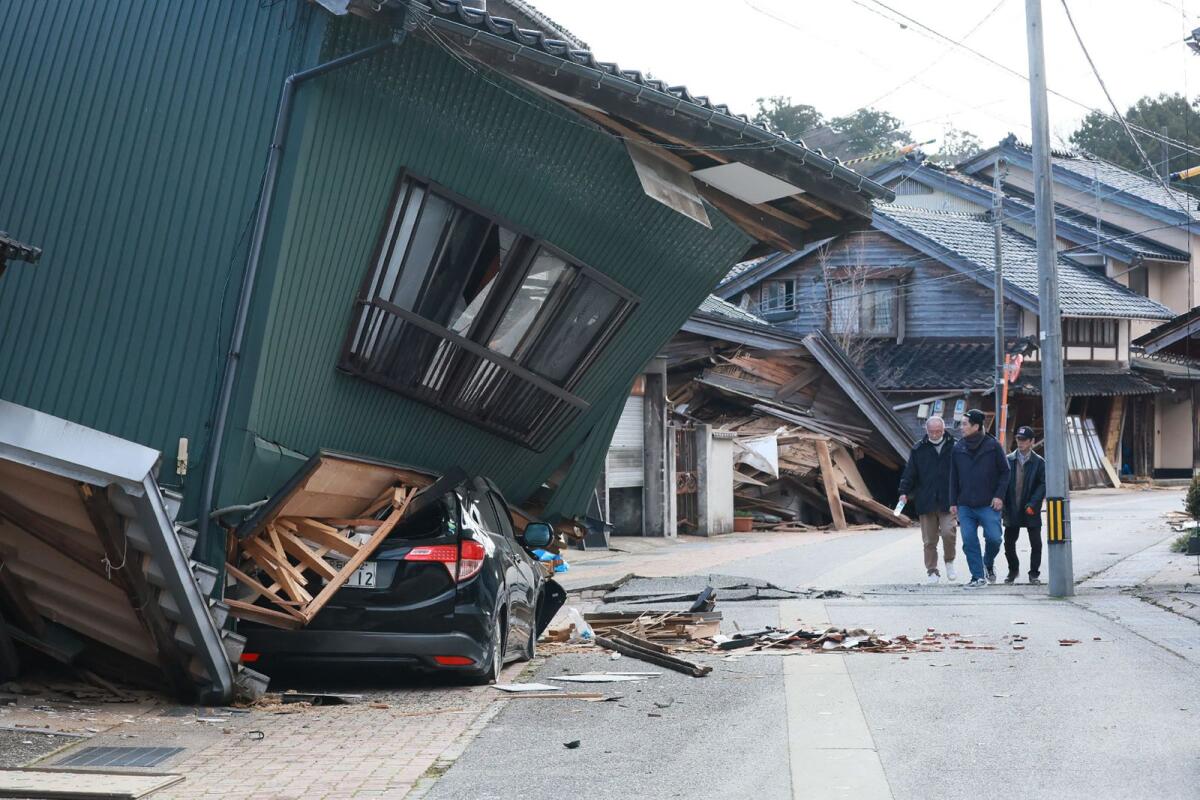 People walk past a badly damaged house in the city of Nanao, Ishikawa Prefecture, on January 2, 2024, a day after a major 7.5 magnitude earthquake struck the Noto region in Ishikawa prefecture. — AFP
