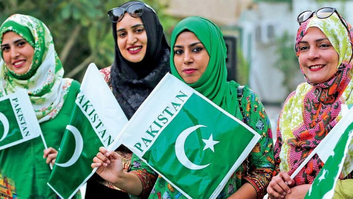 Pakistani women and (below) schoolchildren hold national flags during Pakistan Day celebration at the embassy in Abu Dhabi 