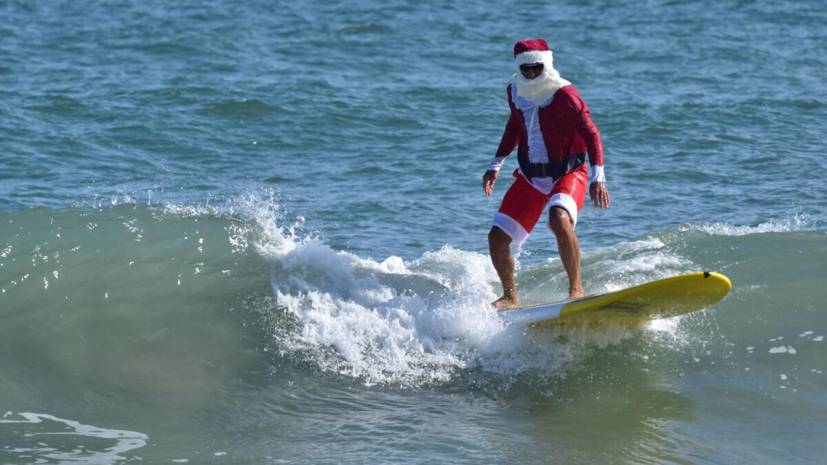 A person dressed in Santa Claus costume surfs in Cocoa Beach, Florida, U.S. December 23, 2020.