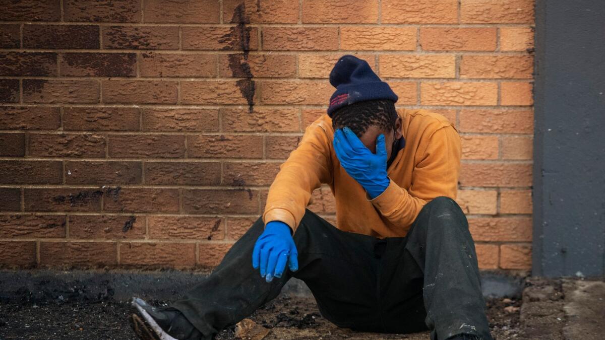 A family member reacts after police officers removed the body his brother who was found inside a burned shop, in Johannesburg, South Africa, on Sunday.