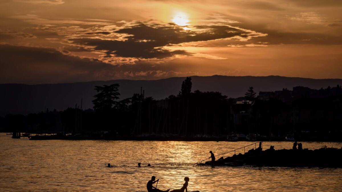 The silhouette of a couple is seen during a sunset as they sit on a paddleboard in the Lake Geneva off the village of Lutry, western Switzerland as heatwave sweeps across Europe. Photo: AFP
