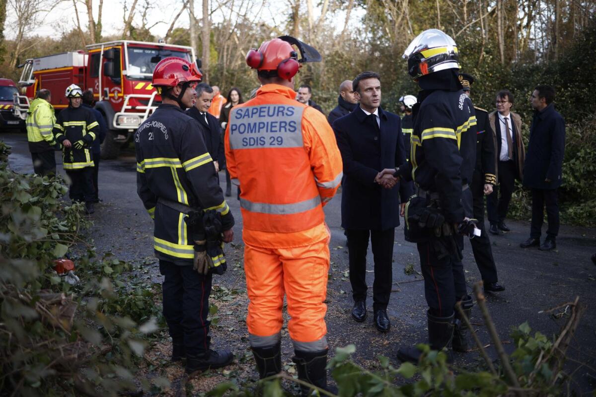 France's President Emmanuel Macron shakes hands with firefighters. — AFP