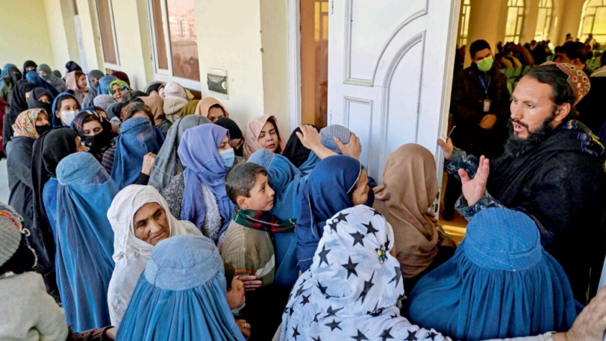 A Taliban fighter guards at an entrance as women wait in a queue during a World Food Programme cash distribution in Kabul. — AFP