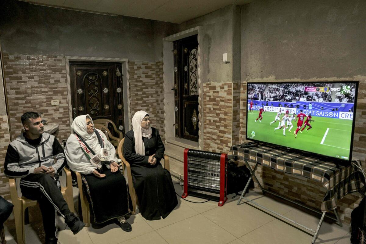 The grandmother (second left) of Palestine captain Musab al-Battat prays as she watches the match between Qatar and Palestine. — AFP