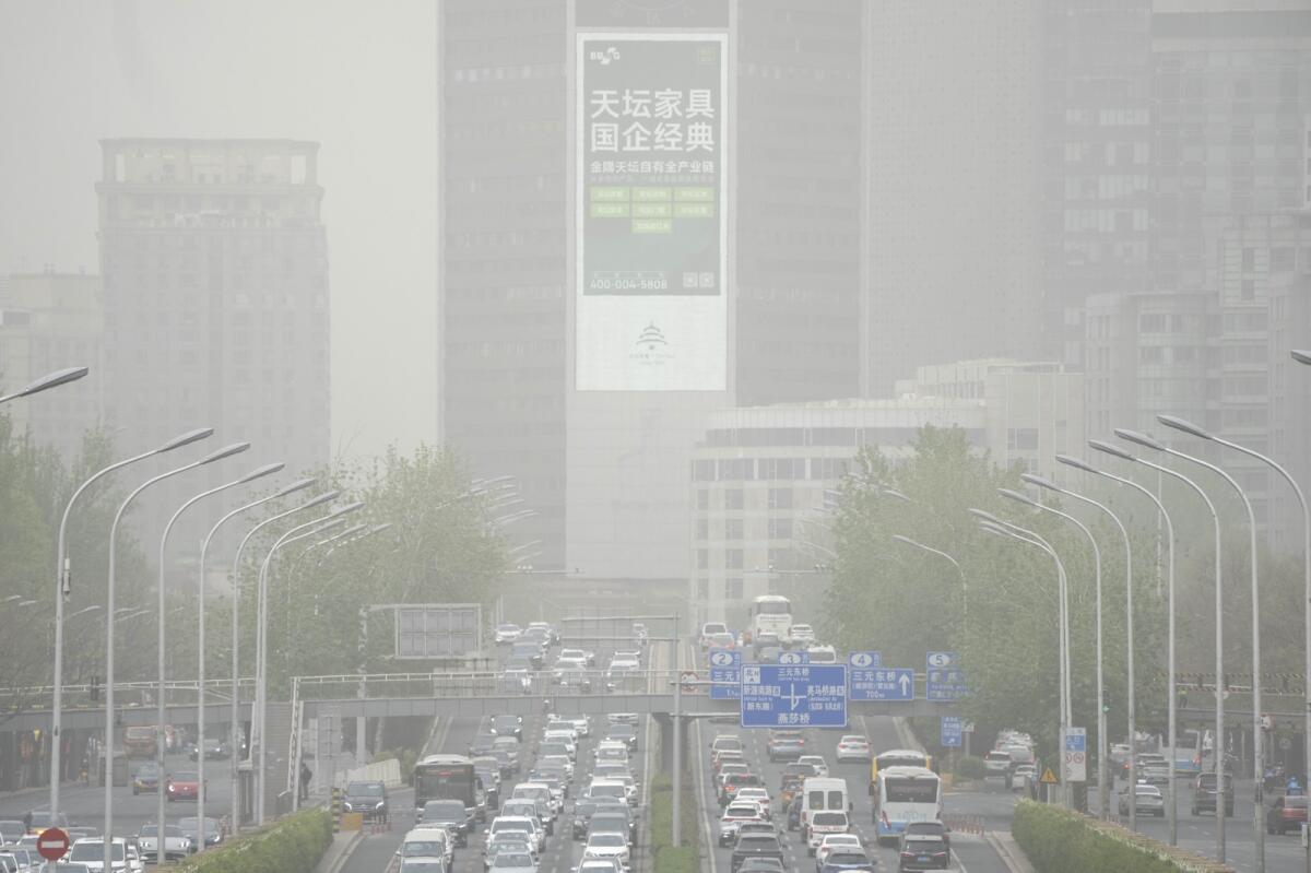 Cars drive an along expressway during a dust and sandstorm in Beijing, on Thursday. — AP