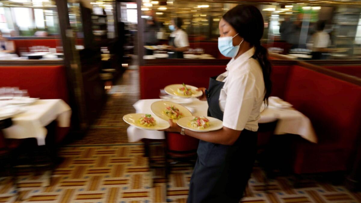 A waiter serves dishes in a dining room at Au Petit Riche restaurant in Paris as cafes, bars and restaurants reopen indoor dining rooms. — Reuters